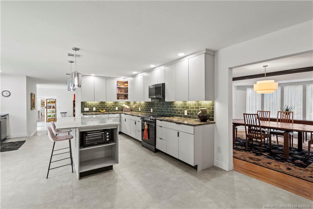 1001 South 11th Street Fort Pierce, FL 34950 - Photo 7 of 80 a kitchen with stainless steel appliances kitchen island granite countertop a stove refrigerator and cabinets