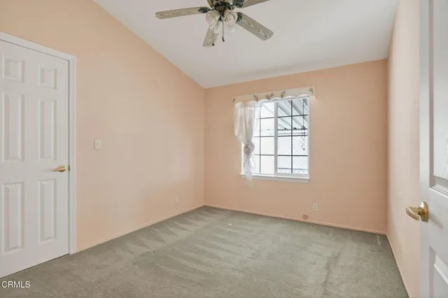 an empty room with a chandelier fan and windows