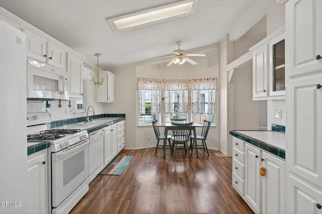 a kitchen with stainless steel appliances granite countertop hardwood floor sink stove dining table and chairs
