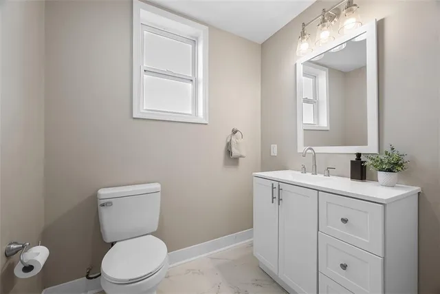 a bathroom with a toilet a sink a vanity and mirror