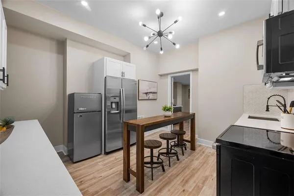 a kitchen with stainless steel appliances a dining table chairs refrigerator and sink