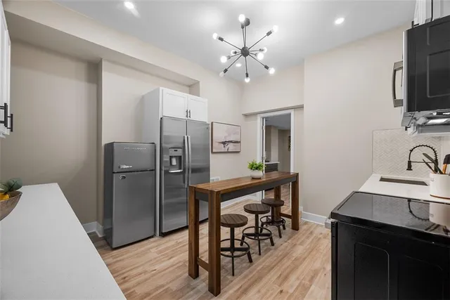 a kitchen with stainless steel appliances a dining table chairs refrigerator and sink