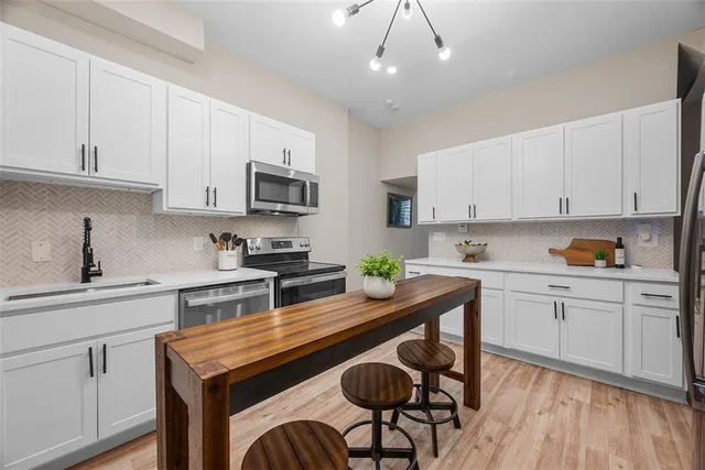 a kitchen with stainless steel appliances granite countertop a sink a stove a refrigerator cabinets and chairs