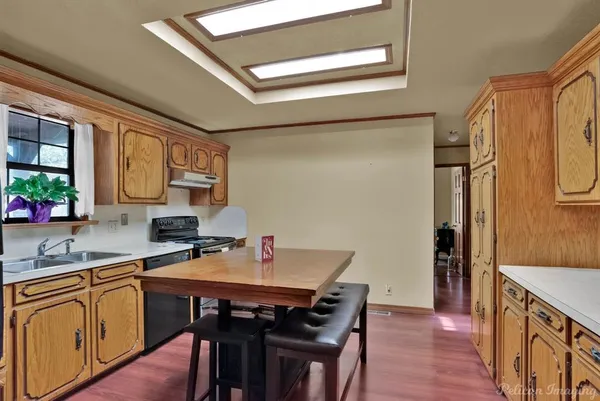 a kitchen with stainless steel appliances a sink a stove and wooden floors