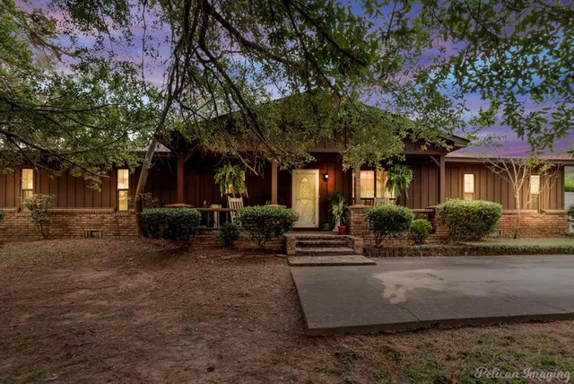 a view of house with yard outdoor seating and covered with trees