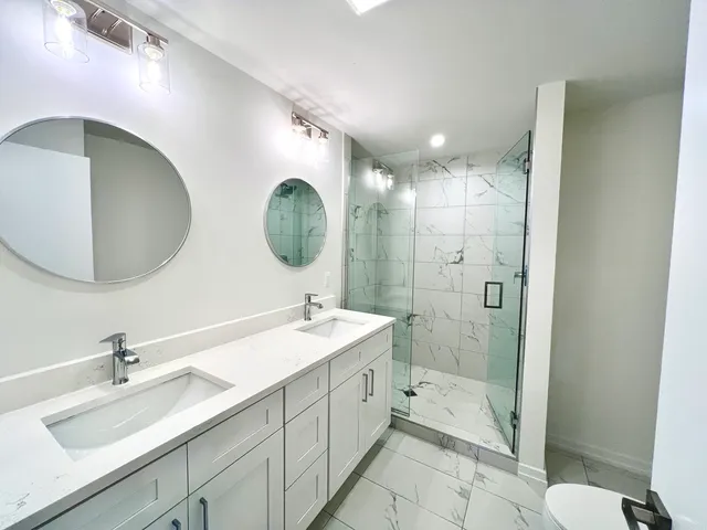 a bathroom with a double vanity sink mirror and shower
