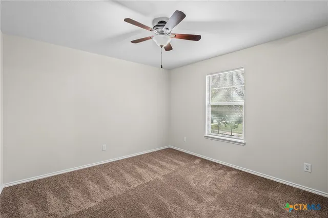 an empty room with ceiling fan and window