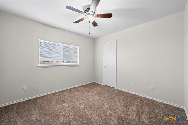 a view of an empty room with a ceiling fan and a window