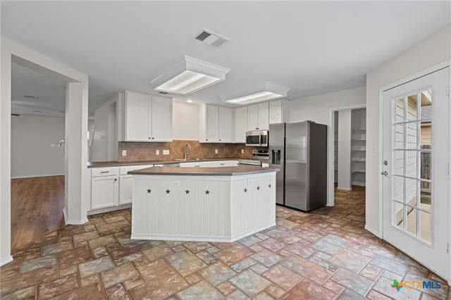 a kitchen with granite countertop a refrigerator a stove a sink and a refrigerator