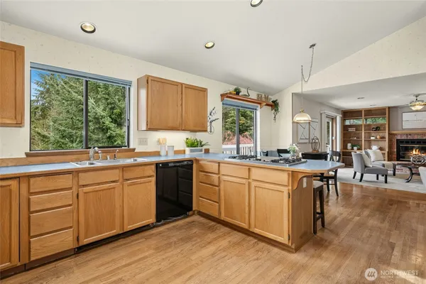 a kitchen with stainless steel appliances granite countertop wooden cabinets a sink a stove a dining table and chairs