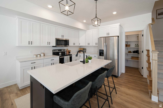 461 West 490 North Lindon, UT 84042 - Photo 4 of 18 Kitchen with white cabinets, appliances with stainless steel finishes, light wood-style flooring, a breakfast bar, and decorative light fixtures