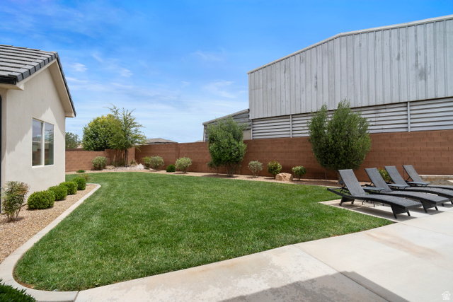 2278 Tawny Ridge Circle St. George, UT 84790 - Photo 55 of 61 Expansive green lawn with mature landscaping, a concrete patio, and a block wall perimeter.