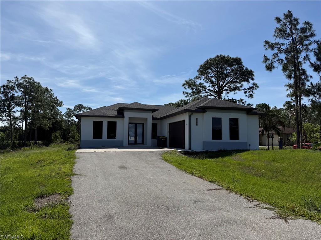 Contemporary stucco exterior with a dark shingle roof, double-door entry, attached two-car garage, and a paved driveway