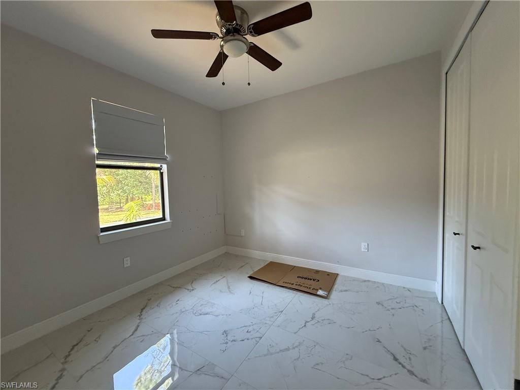 4768 40th Street Northeast Naples, FL 34120 - Photo 11 of 18 Interior room featuring large format tile flooring, a window with a roller shade, and a ceiling fan with integrated lighting