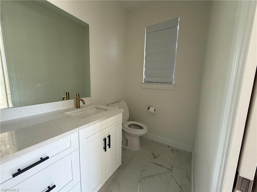 4768 40th Street Northeast Naples, FL 34120 - Photo 14 of 18 Bathroom vanity featuring a quartz countertop with integrated sink and brass-finish faucet