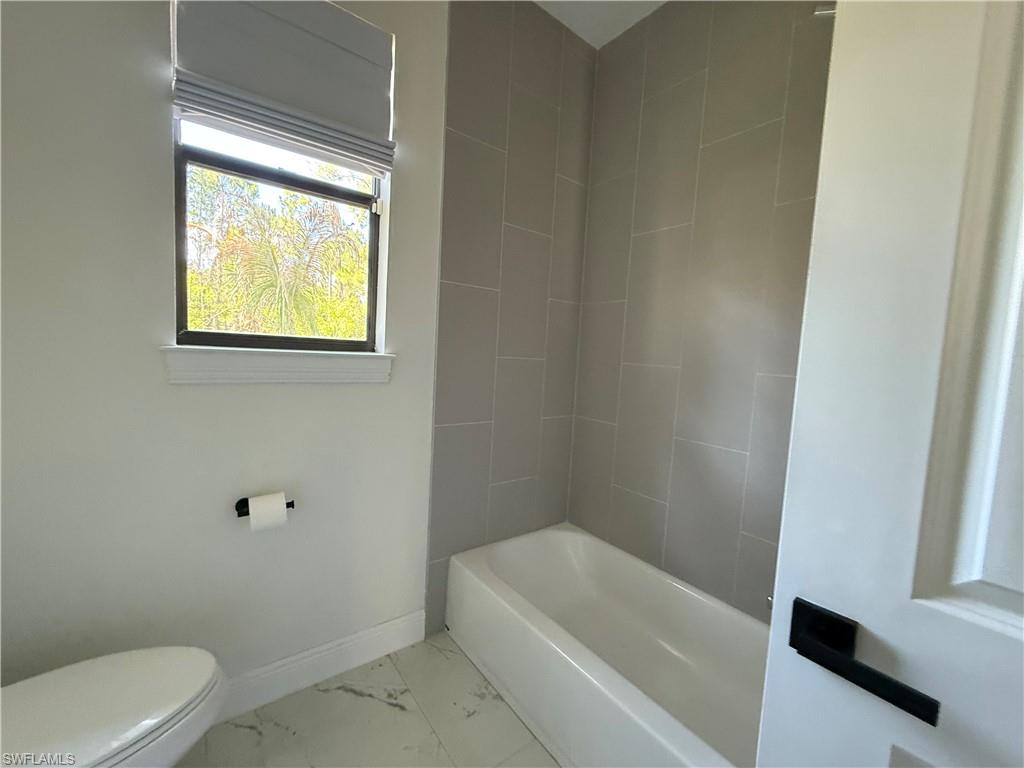 4768 40th Street Northeast Naples, FL 34120 - Photo 16 of 18 Bathroom featuring a white soaking tub, light gray subway tile surround, and a white toilet