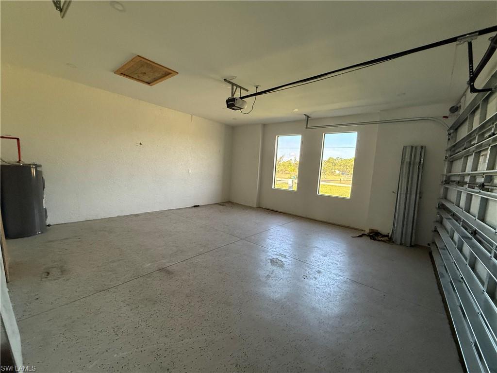 4768 40th Street Northeast Naples, FL 34120 - Photo 17 of 18 Spacious garage featuring a durable concrete floor, three windows providing natural light, an overhead garage door opener, and attic access
