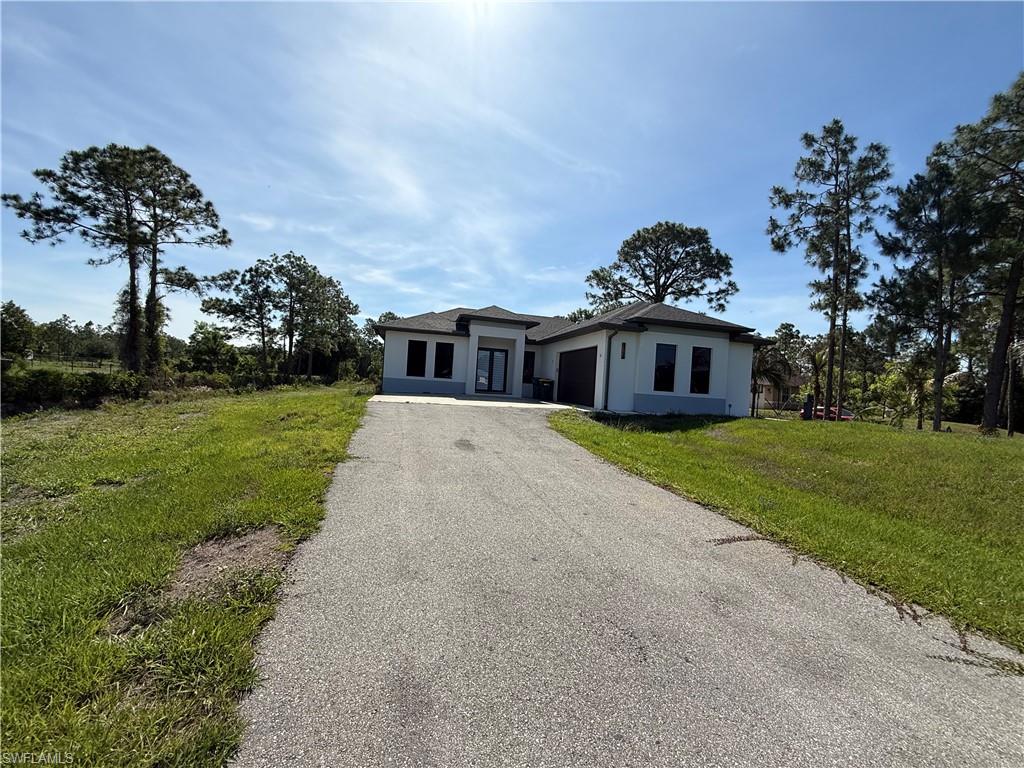 4768 40th Street Northeast Naples, FL 34120 - Photo 2 of 18 Contemporary single-story home featuring a dark shingle roof, white stucco exterior, and dark-framed windows