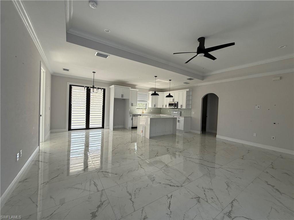 4768 40th Street Northeast Naples, FL 34120 - Photo 3 of 18 Spacious open-concept living area featuring large format tile flooring, crown molding, and a modern kitchen with white cabinetry