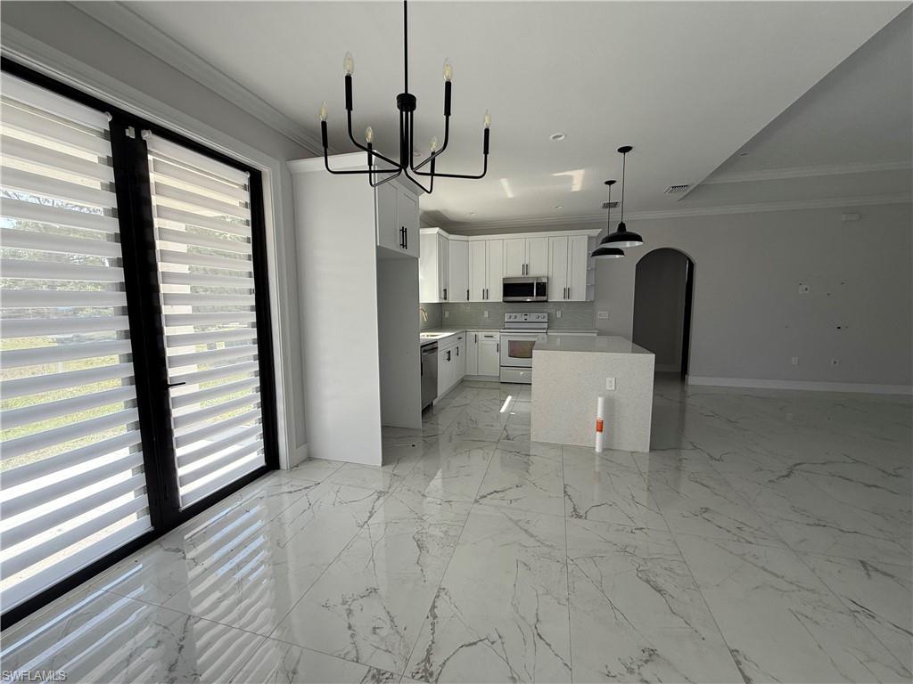 4768 40th Street Northeast Naples, FL 34120 - Photo 4 of 18 Bright open-concept kitchen featuring white shaker cabinetry, stainless steel appliances, and a central island with a light-toned countertop