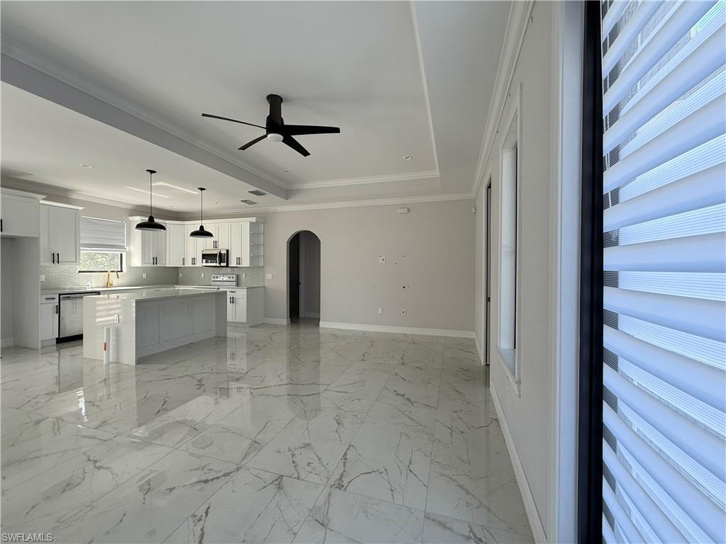 4768 40th Street Northeast Naples, FL 34120 - Photo 5 of 18 Spacious open concept living area featuring large format marble-look tile flooring, a modern kitchen island with pendant lighting, white shaker cabinetry, and a ceiling fan