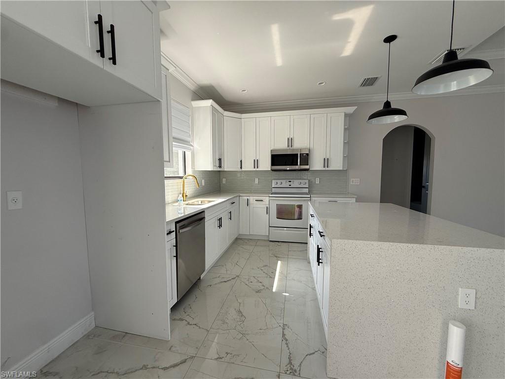 4768 40th Street Northeast Naples, FL 34120 - Photo 7 of 18 Modern kitchen featuring white shaker cabinetry with black hardware, stainless steel appliances, and a light-toned backsplash