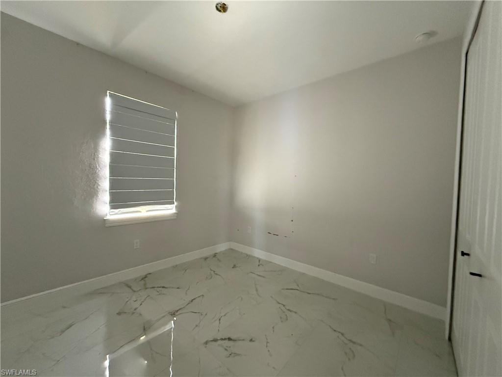 4768 40th Street Northeast Naples, FL 34120 - Photo 10 of 18 Room featuring white walls with white baseboards, a window with horizontal blinds, and a white tile floor with gray veining