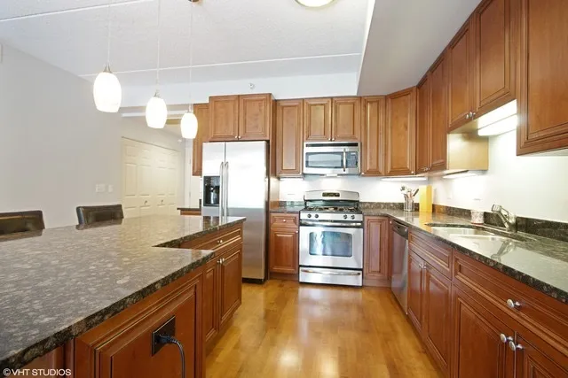 a kitchen with granite countertop a sink stove and refrigerator