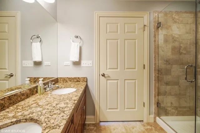 a bathroom with a granite countertop shower a mirror and