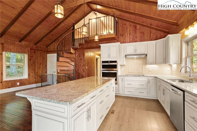 a view of an empty room with wooden floor and windows