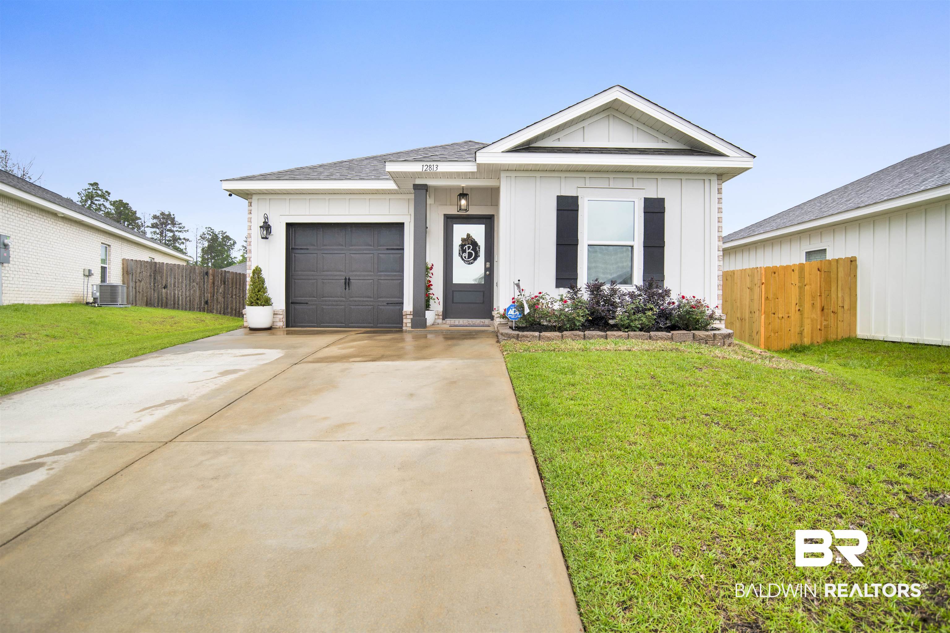 12813 Patriot Way Daphne, AL 36527 - Photo 22 of 23 Contemporary white siding exterior with a dark gray garage door, covered front entry, and a paved driveway