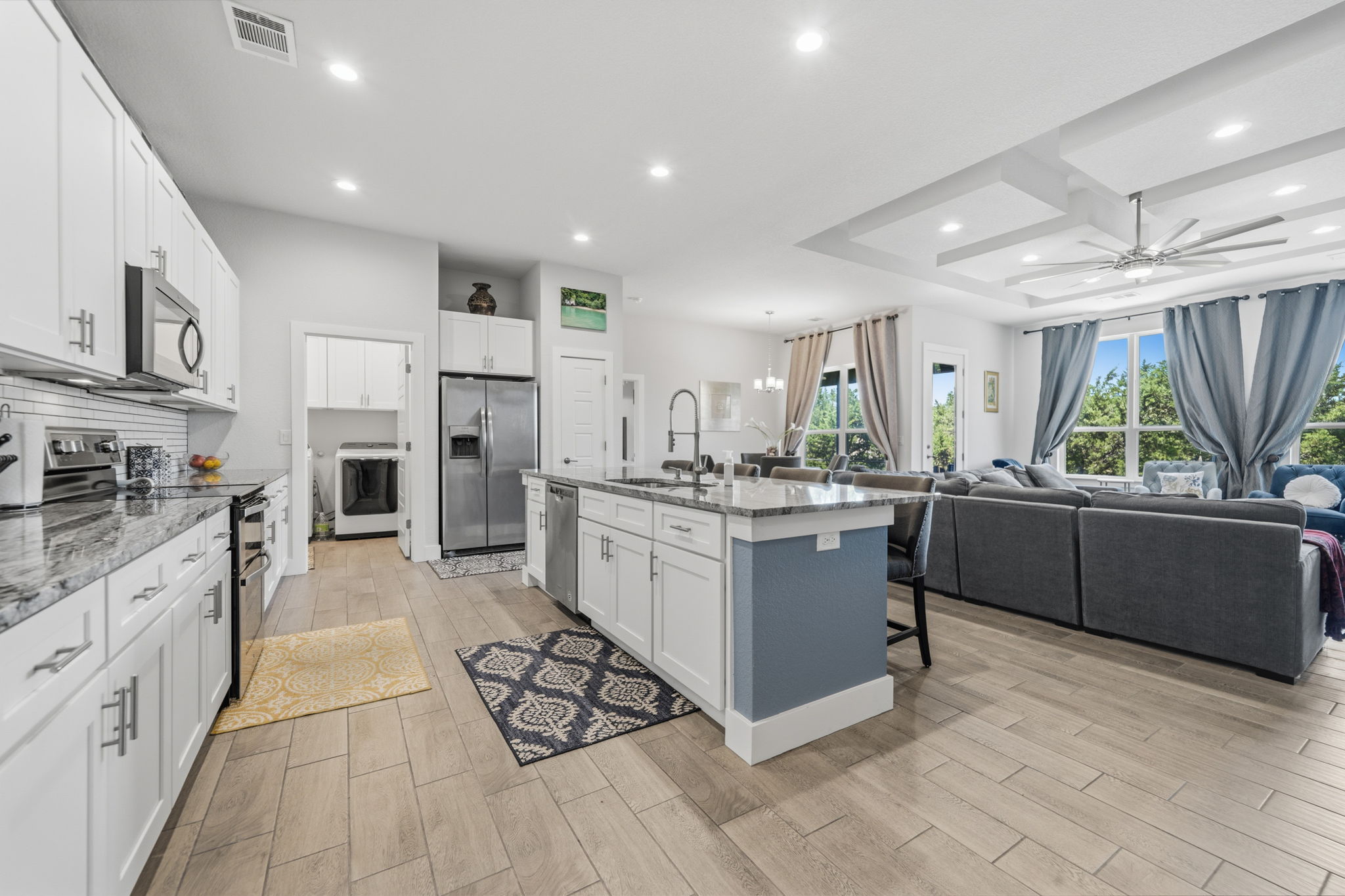 18605 Masters Cove Point Venture, TX 78645 - Photo 6 of 40 Open-concept living space featuring a kitchen with white cabinetry, stainless steel appliances, and a central island with counter seating