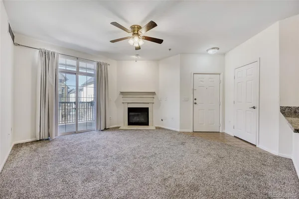 a view of an empty room with kitchen and fireplace