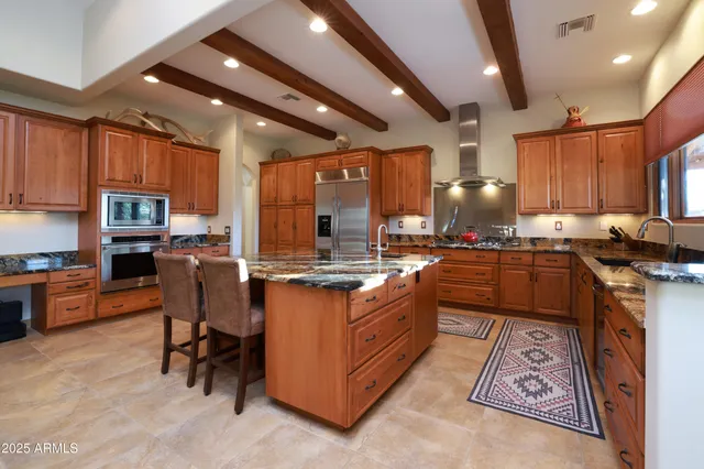 a kitchen with stainless steel appliances granite countertop a stove top oven a sink dishwasher a dining table and chairs with wooden floor