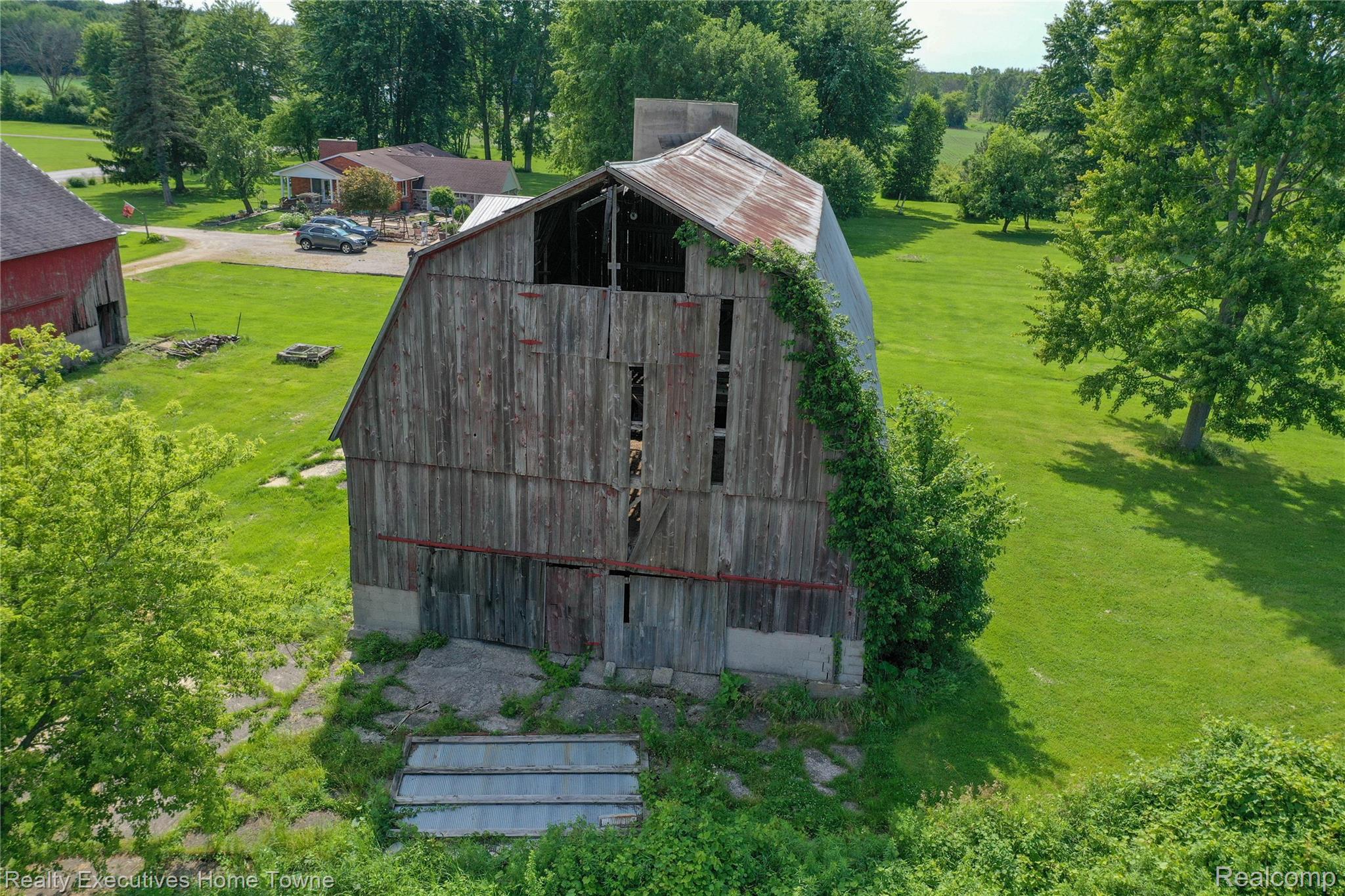 8728 Rynn Road Avoca, MI 48006 - Photo 43 of 53 Weathered wood barn with a corrugated metal roof, surrounded by expansive green lawn and mature trees