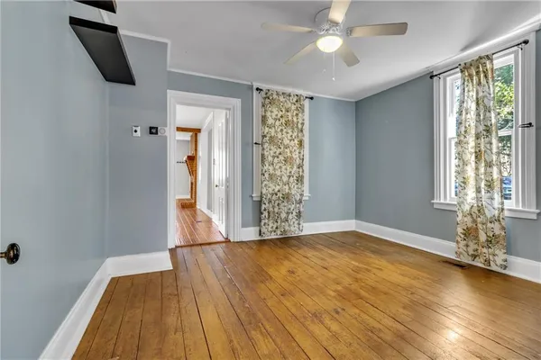 a view of an empty room with window and wooden floor