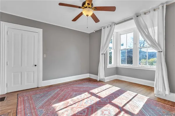 a view of an empty room with window and wooden floor