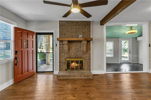 a view of an empty room with wooden floor fireplace and a window