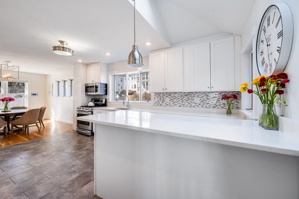21 Arborough Road Boston, MA 02131 - Photo 11 of 40 a kitchen with stainless steel appliances a sink a stove top oven a chimney and a center island