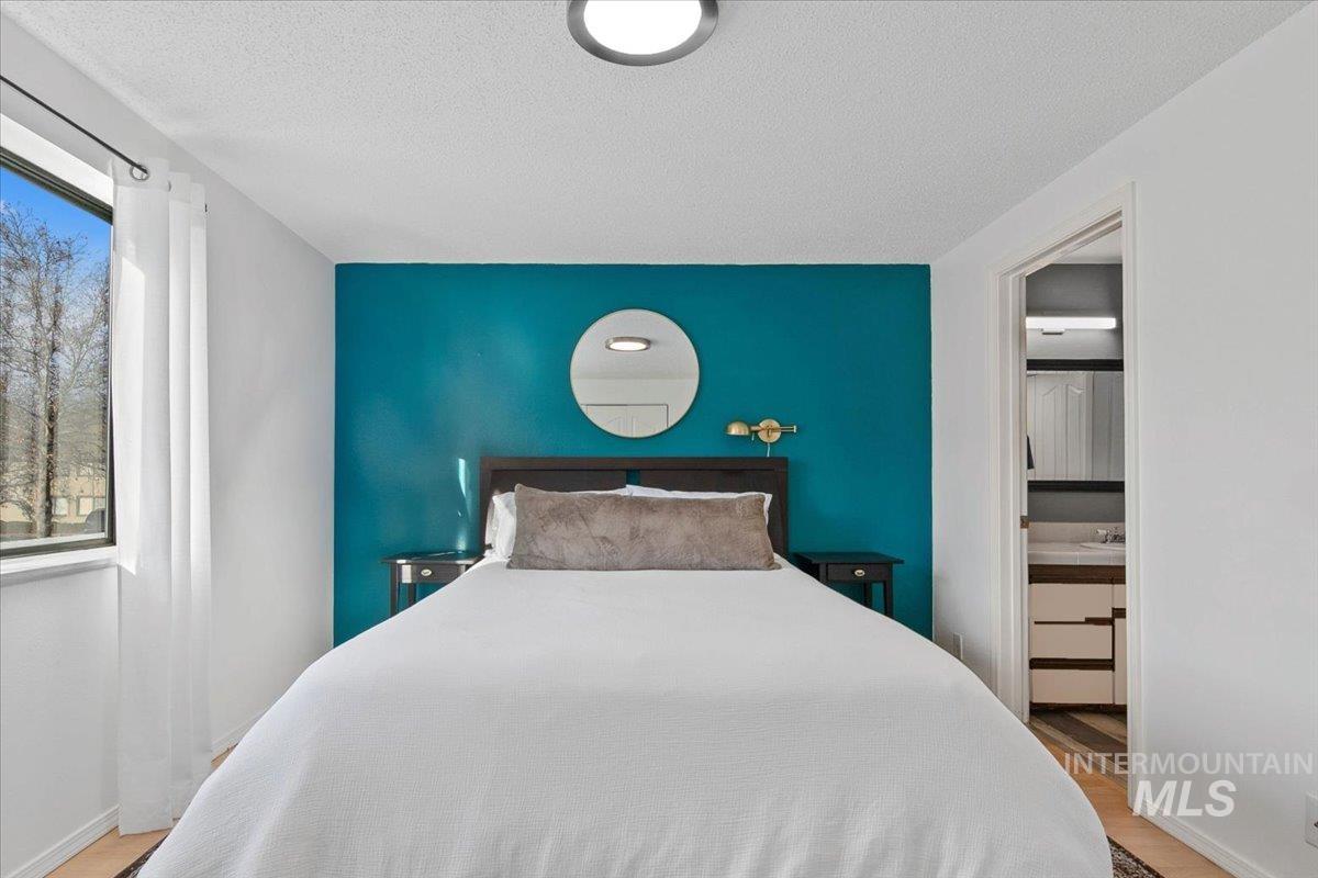 3651 South Gekeler Lane, Unit 96 Boise, ID 83706 - Photo 14 of 38 Bedroom with an accent wall, light wood-style floors, and a textured ceiling
