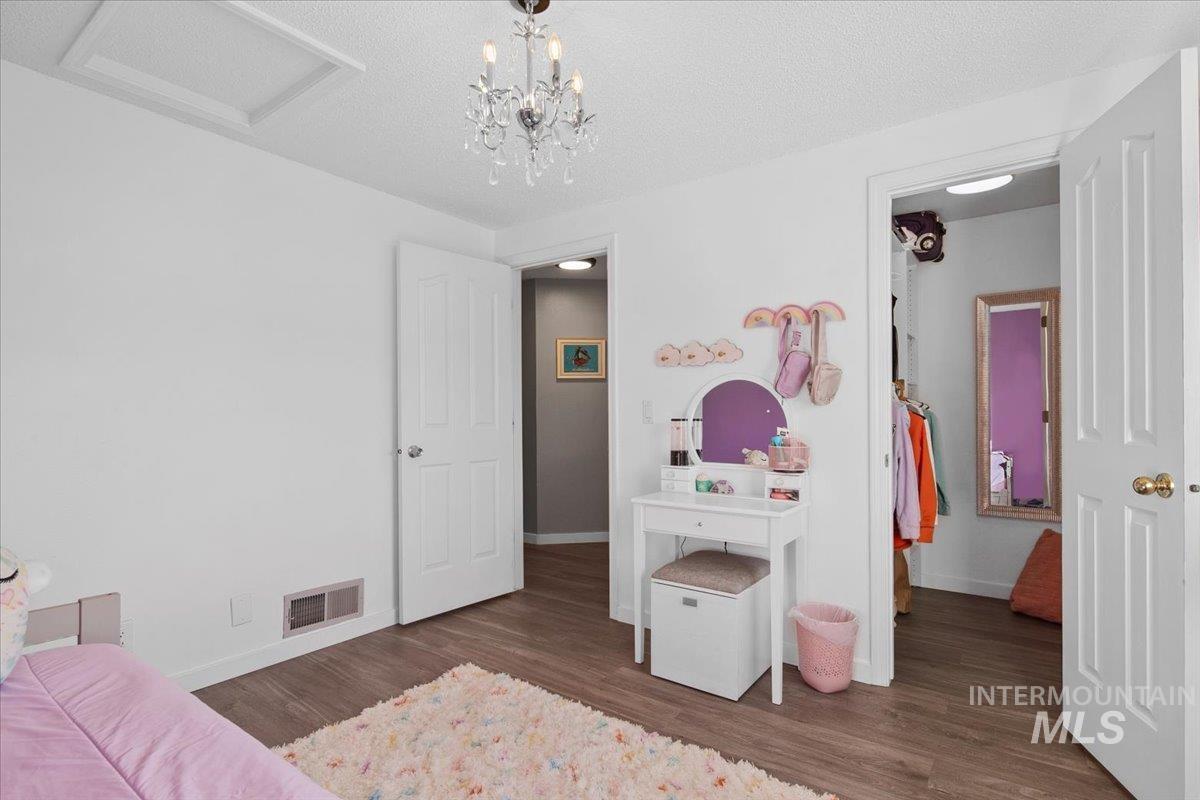 3651 South Gekeler Lane, Unit 96 Boise, ID 83706 - Photo 30 of 38 Bedroom featuring dark wood-style flooring, a textured ceiling, attic access, and a chandelier