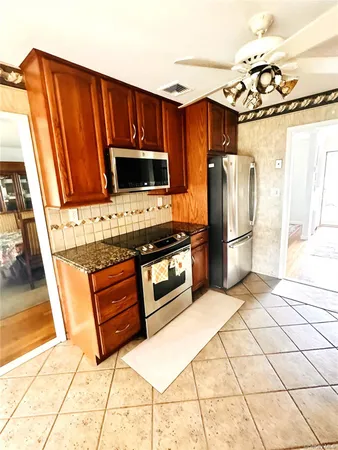 a kitchen with granite countertop a refrigerator and a stove top oven