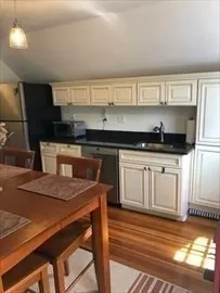 a kitchen with granite countertop a stove a sink and white cabinets