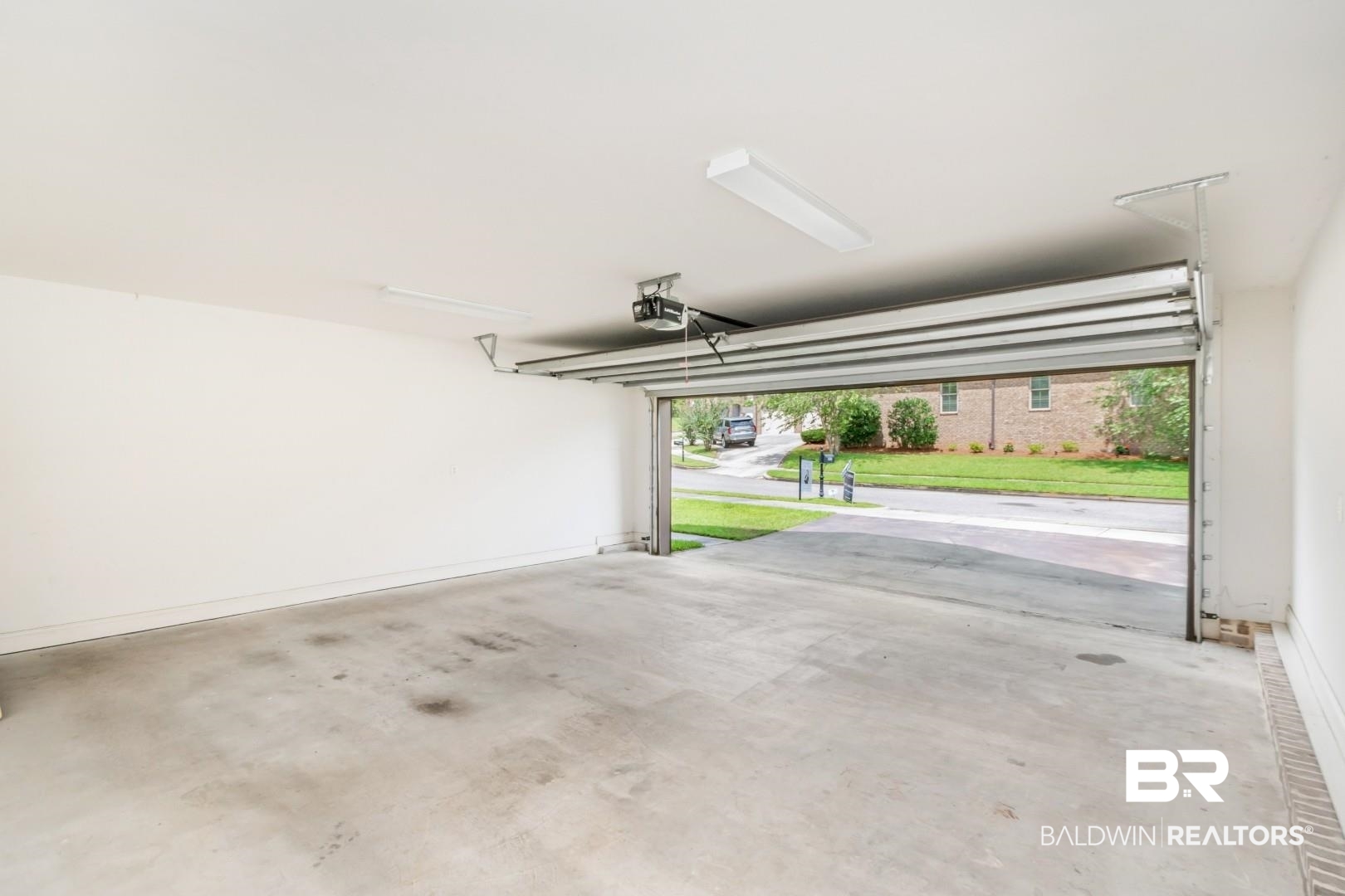 3528 Rue Royal Mobile, AL 36693 - Photo 53 of 53 Spacious garage with a concrete floor, white walls, and a visible garage door opener