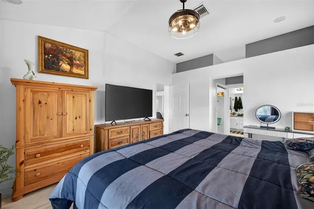 a bedroom with a bed and a flat tv screen on dresser