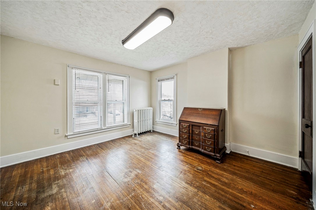 977 West Prospect Road Ashtabula, OH 44004 - Photo 26 of 42 Unfurnished room featuring a textured ceiling, radiator heating unit, and dark wood-style floors