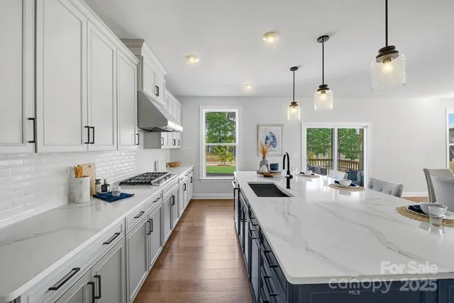 a kitchen with kitchen island granite countertop lots of counter top space a sink a stove and a window