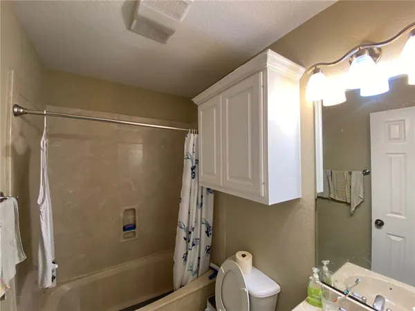 a bathroom with a granite countertop bathtub shower sink vanity and toilet