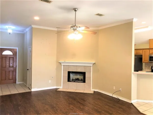 a view of an empty room with wooden floor and a fireplace