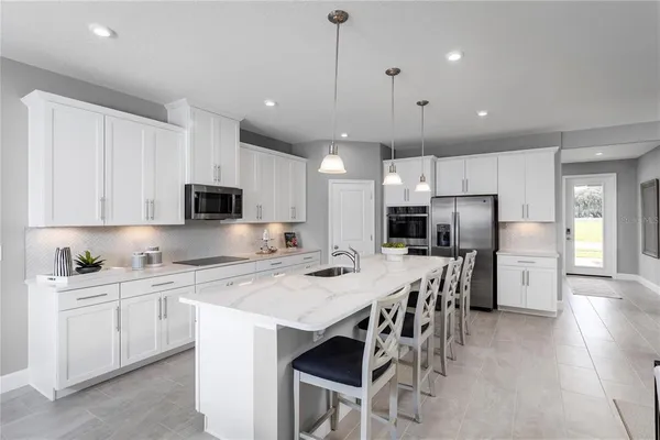 a kitchen with stainless steel appliances kitchen island granite countertop a table chairs refrigerator and microwave